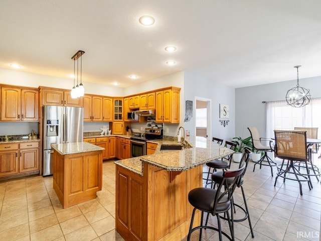 kitchen featuring light stone counters, a wealth of natural light, a peninsula, stainless steel appliances, and a sink