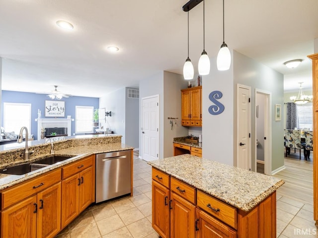 kitchen featuring a sink, stainless steel dishwasher, open floor plan, light tile patterned flooring, and a fireplace