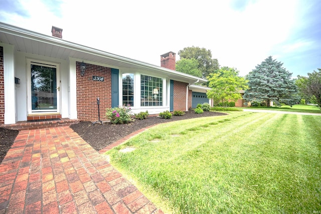 exterior space with brick siding, an attached garage, a chimney, and a front lawn