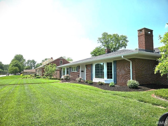 single story home with brick siding, a chimney, and a front yard