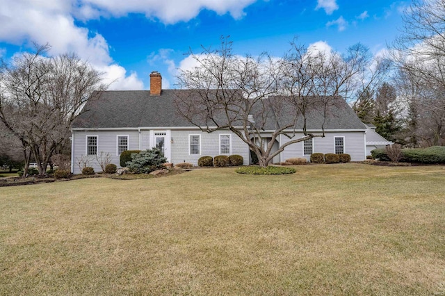 view of front facade featuring a chimney, a front yard, and a shingled roof