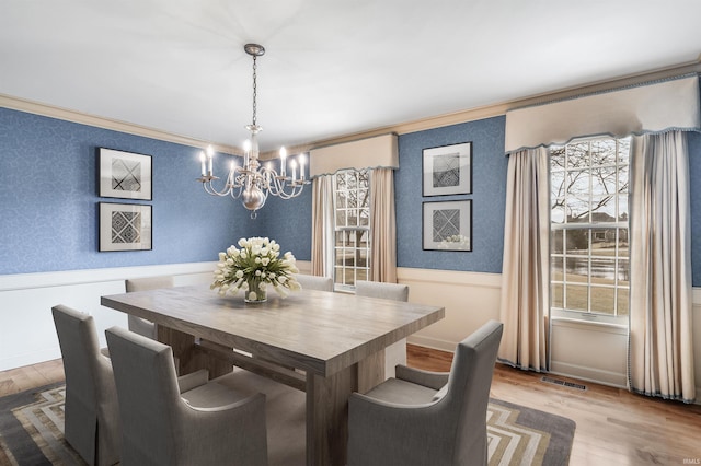 dining space featuring a wainscoted wall, wallpapered walls, and crown molding