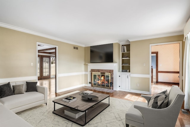 living room featuring light wood-type flooring, visible vents, ornamental molding, and a fireplace