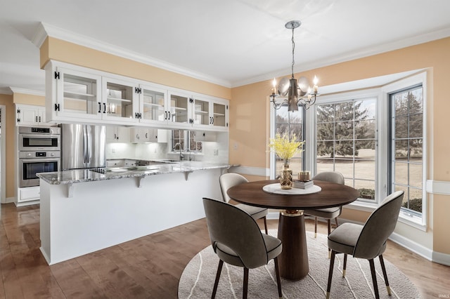 dining room with a chandelier, wood finished floors, baseboards, and ornamental molding