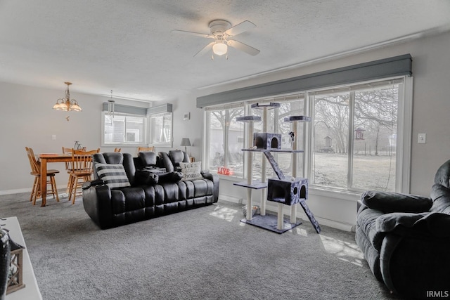 living area with baseboards, carpet, ceiling fan, and a textured ceiling