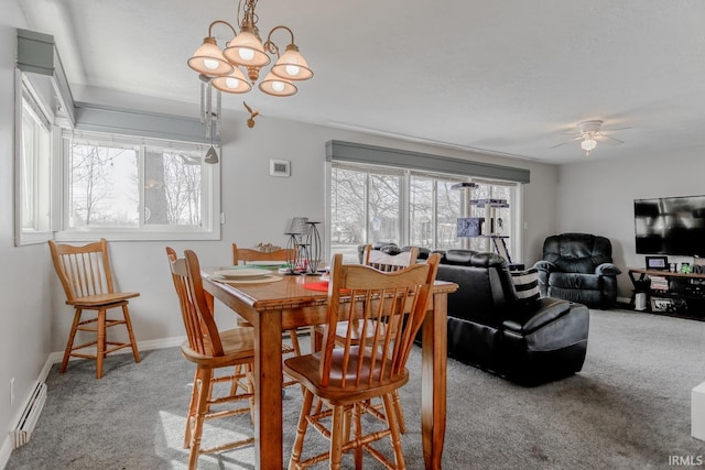 carpeted dining space featuring a healthy amount of sunlight, ceiling fan with notable chandelier, a baseboard heating unit, and baseboards