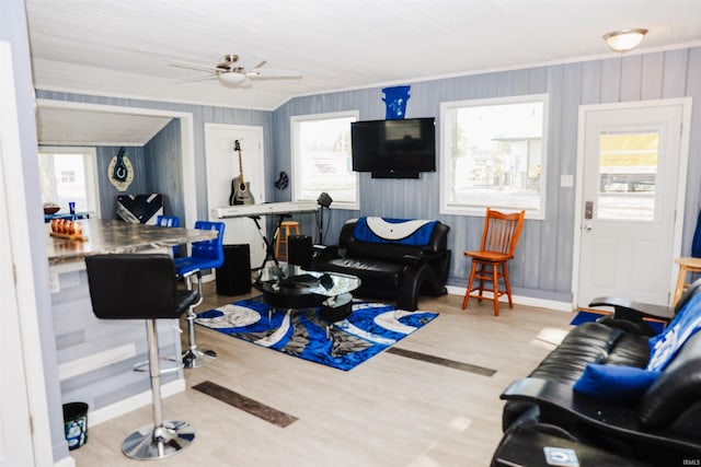 living area with ornamental molding, a ceiling fan, baseboards, and wood finished floors