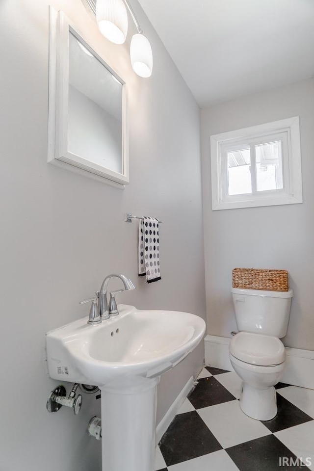 half bath featuring tile patterned floors, toilet, and baseboards