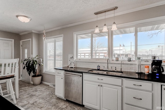 kitchen with a sink, stainless steel dishwasher, dark countertops, white cabinetry, and crown molding