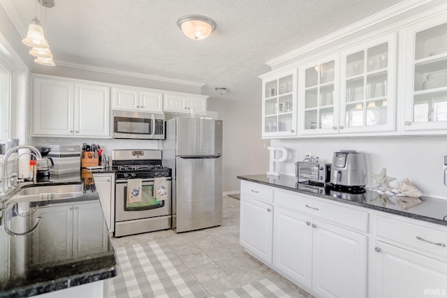 kitchen featuring glass insert cabinets, dark stone counters, white cabinets, stainless steel appliances, and a sink