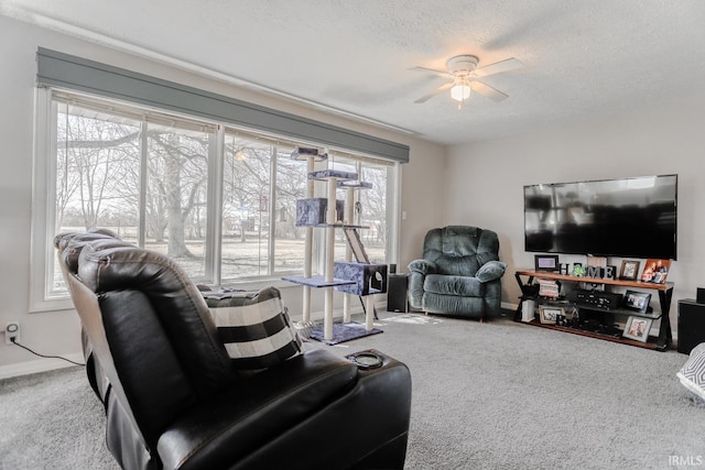 carpeted living room featuring a ceiling fan, baseboards, and a textured ceiling