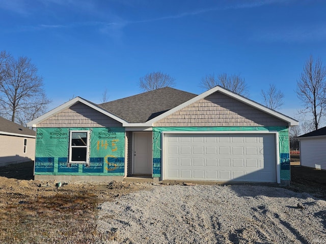 view of front facade with a garage, driveway, and roof with shingles