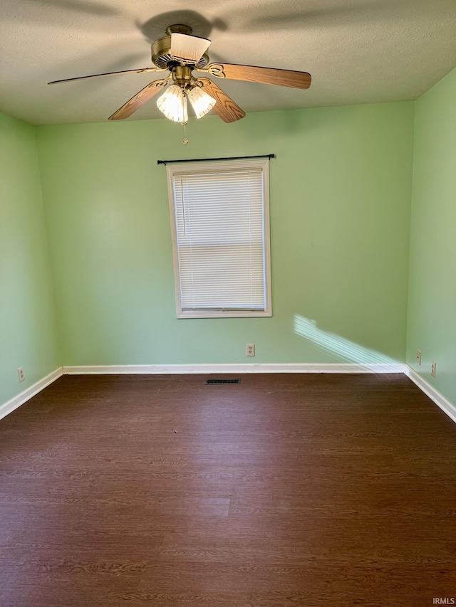 spare room with visible vents, baseboards, dark wood-style floors, a textured ceiling, and a ceiling fan