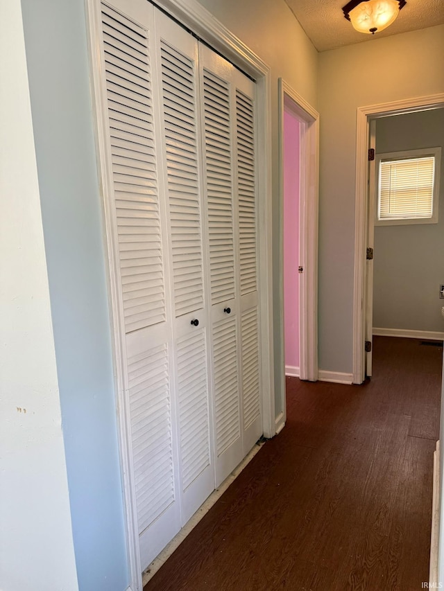 hall with dark wood finished floors and baseboards