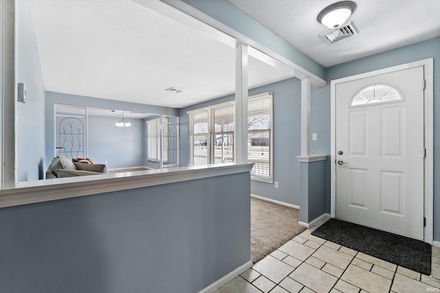 entrance foyer featuring visible vents, light colored carpet, a textured ceiling, and baseboards