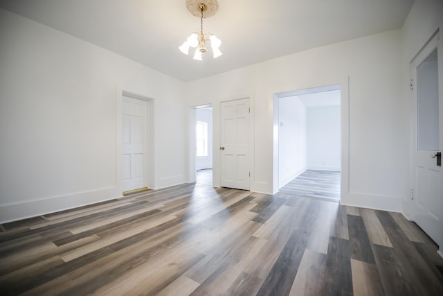 empty room featuring dark wood finished floors, baseboards, and a chandelier