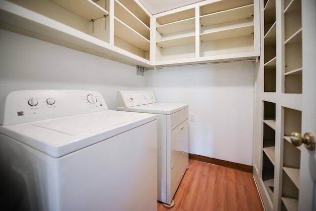 clothes washing area featuring washer and dryer, baseboards, light wood-style flooring, and laundry area