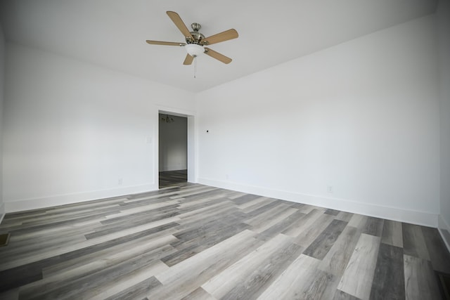 empty room with ceiling fan, baseboards, and wood finished floors