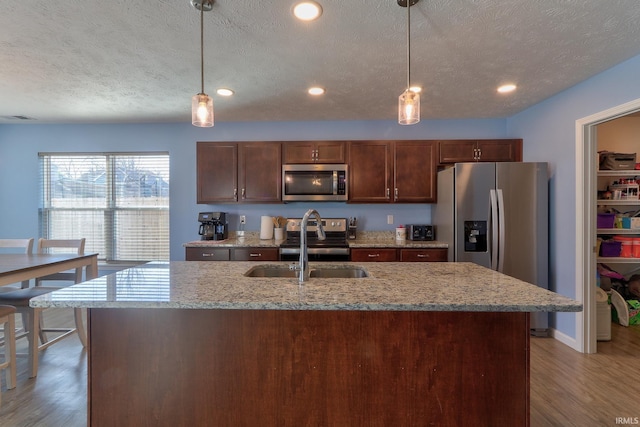 kitchen with light wood-type flooring, visible vents, a textured ceiling, stainless steel appliances, and light stone countertops