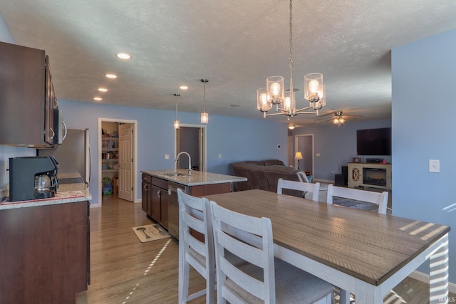 dining area with a ceiling fan, a textured ceiling, wood finished floors, recessed lighting, and a fireplace