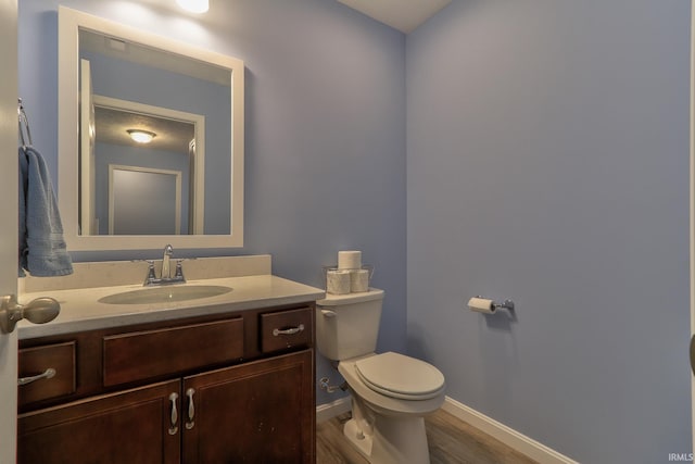 bathroom featuring toilet, vanity, baseboards, and wood finished floors