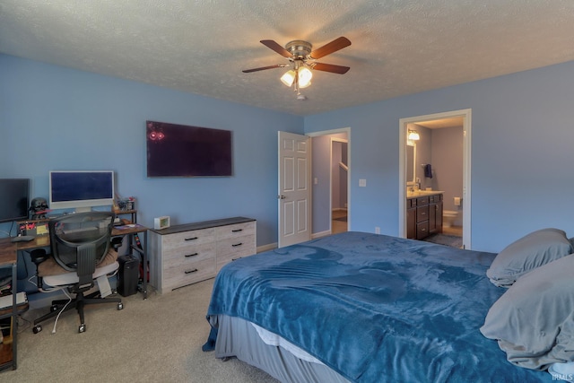 bedroom with a ceiling fan, connected bathroom, light colored carpet, and a textured ceiling