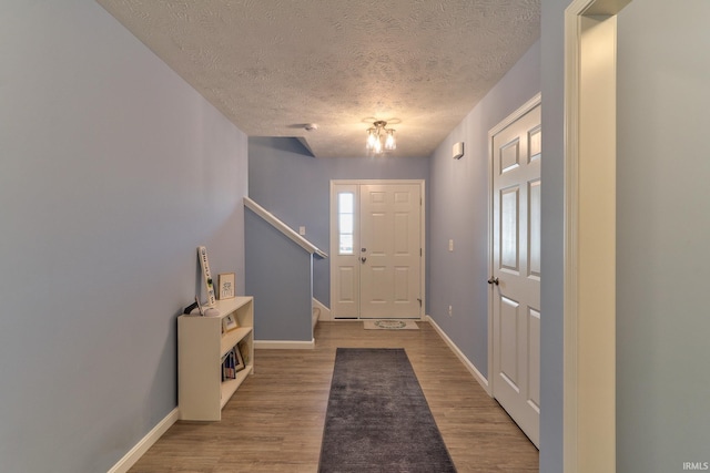 entryway featuring a textured ceiling, baseboards, and wood finished floors