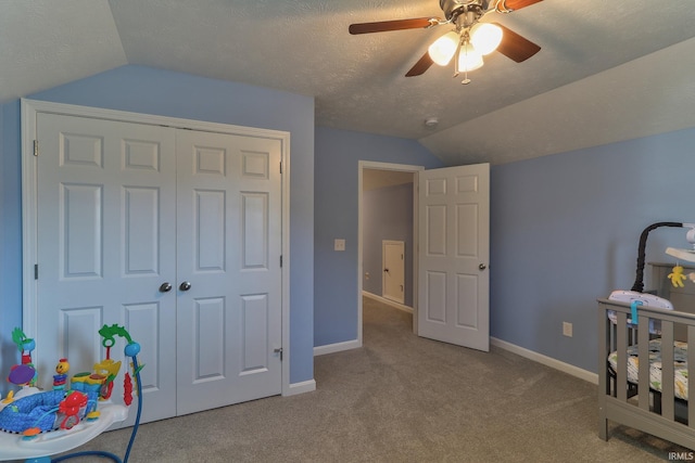 bedroom with a textured ceiling, a closet, carpet floors, baseboards, and vaulted ceiling