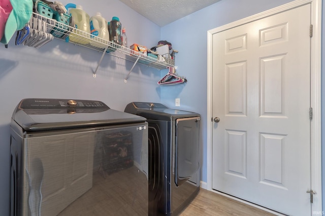 washroom featuring light wood-type flooring, a textured ceiling, independent washer and dryer, and laundry area