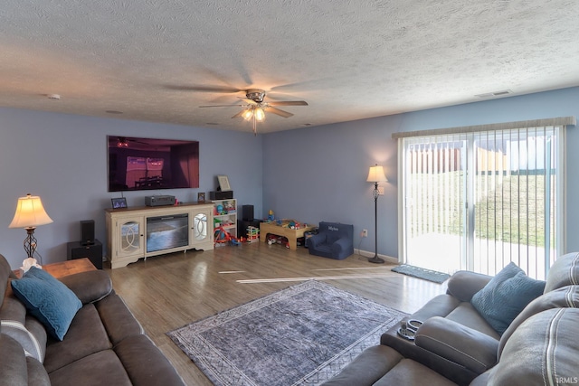 living area featuring visible vents, a textured ceiling, ceiling fan, and wood finished floors