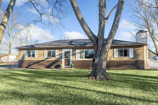 view of front of property with brick siding, a chimney, a front yard, and fence