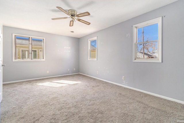 carpeted spare room featuring baseboards and ceiling fan