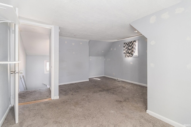 below grade area featuring a textured ceiling, baseboards, and carpet floors