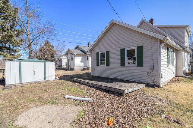 view of side of property featuring a storage unit, an outbuilding, a chimney, and fence