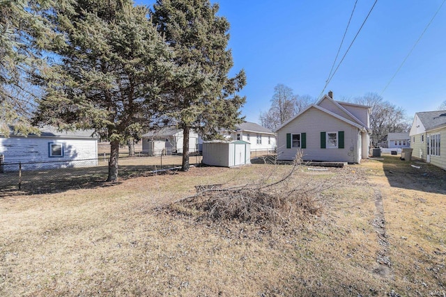 rear view of house with an outbuilding, a storage shed, and fence