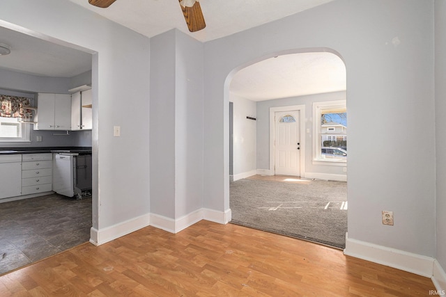 interior space with baseboards, arched walkways, and light wood-type flooring