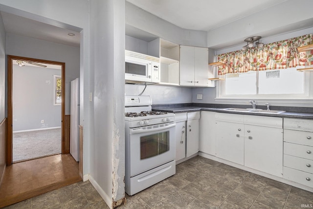 kitchen with white appliances, open shelves, a sink, white cabinetry, and dark countertops