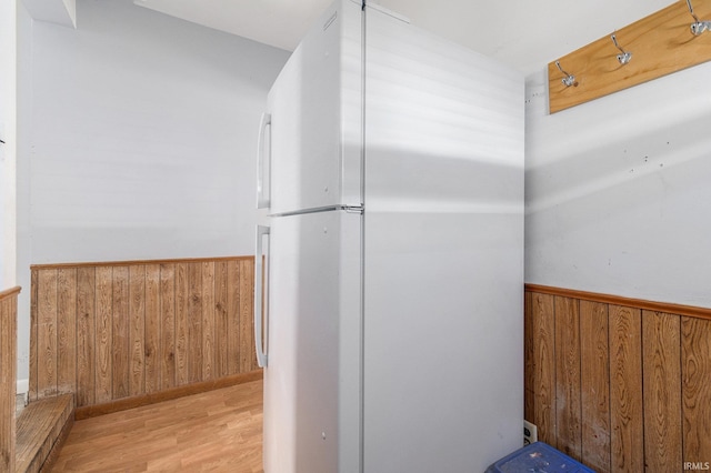 bathroom featuring wooden walls, wood finished floors, and wainscoting