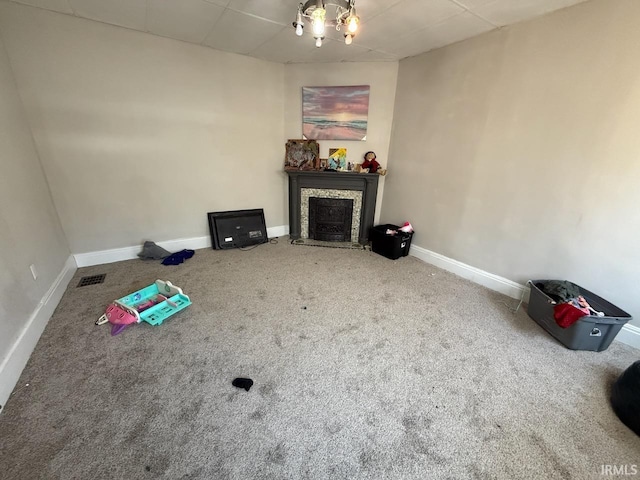 interior space featuring visible vents, baseboards, carpet floors, a fireplace, and a drop ceiling