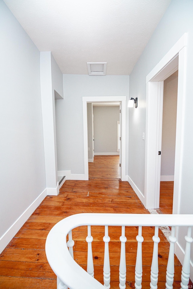 hallway with baseboards, attic access, and wood finished floors