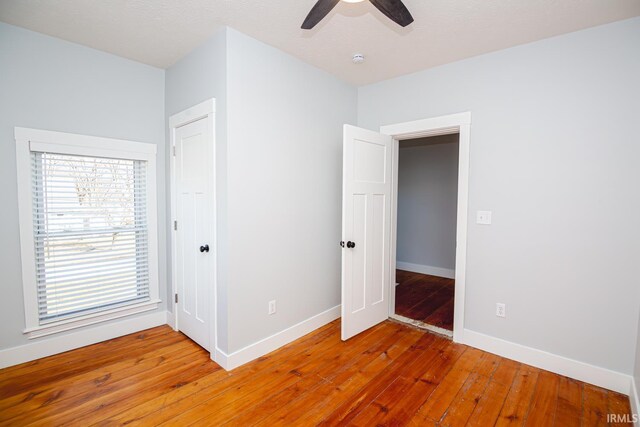 unfurnished bedroom featuring light wood-style floors, baseboards, and ceiling fan