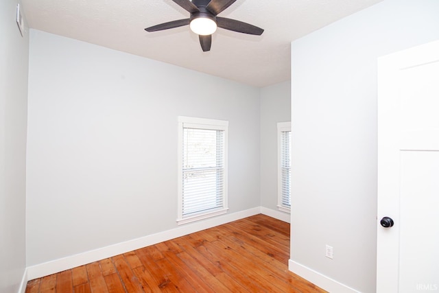 spare room featuring a ceiling fan, light wood-style floors, baseboards, and a textured ceiling