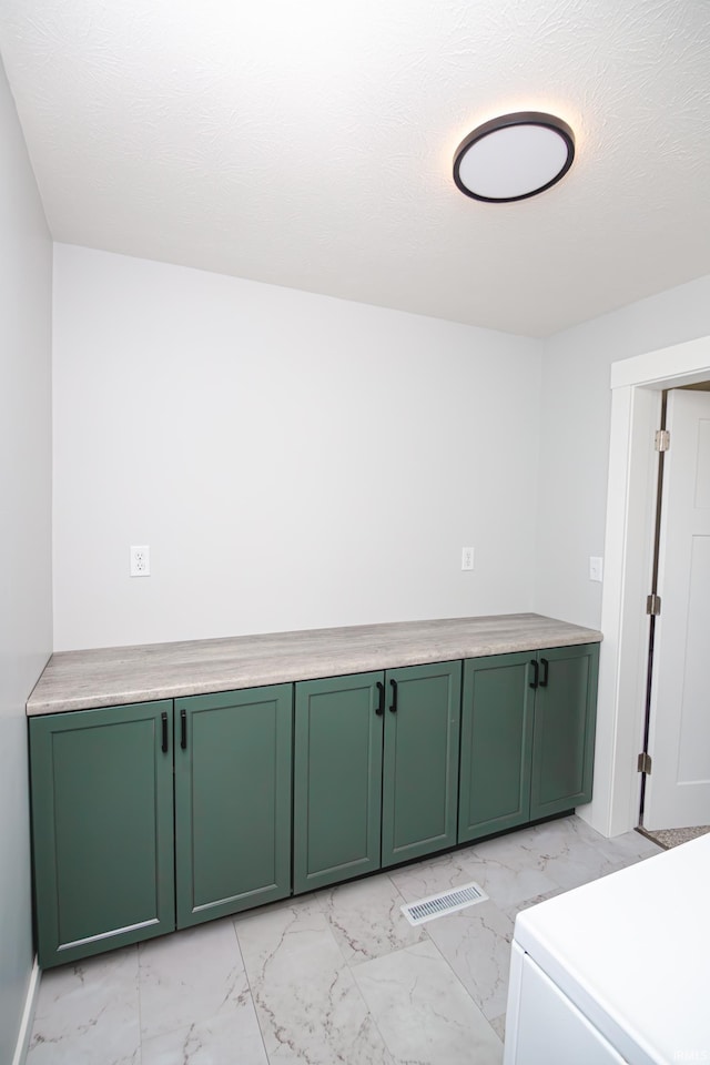 laundry area featuring visible vents, a textured ceiling, and marble finish floor