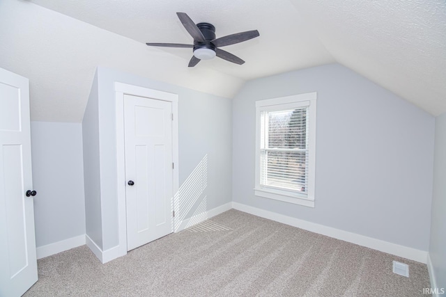 bonus room featuring a textured ceiling, baseboards, carpet, and vaulted ceiling