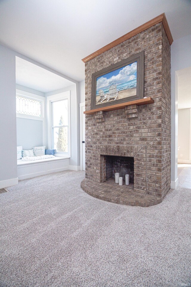 unfurnished living room featuring visible vents, a brick fireplace, baseboards, and carpet floors