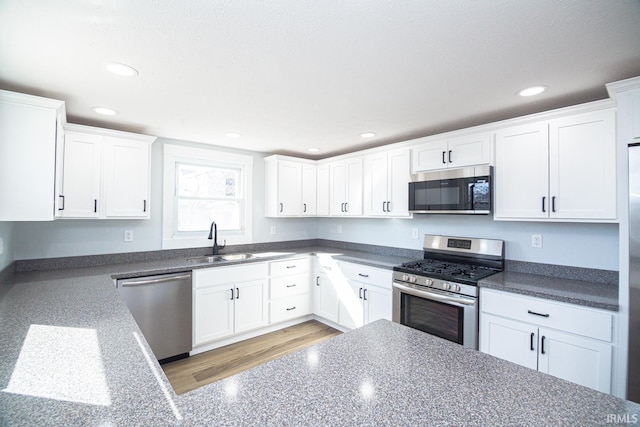 kitchen with a sink, white cabinets, recessed lighting, and stainless steel appliances