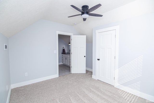 unfurnished bedroom with visible vents, baseboards, lofted ceiling, carpet flooring, and a textured ceiling