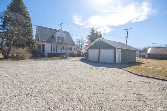 view of front of house with a detached garage and an outbuilding