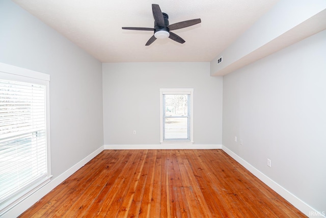 unfurnished room with baseboards, visible vents, wood-type flooring, and ceiling fan