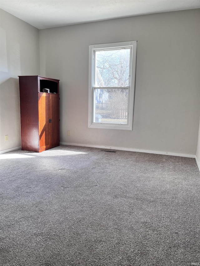 carpeted spare room featuring baseboards and visible vents